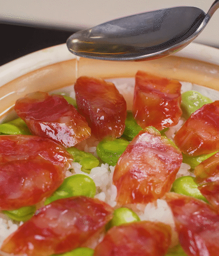 大米出現(xiàn)小孔時開蓋放香腸，往鍋邊淋入少許油，再燜煮8~10分鐘左右。